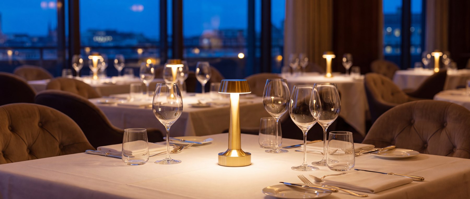 A dining room at dusk where every table carries the same light.