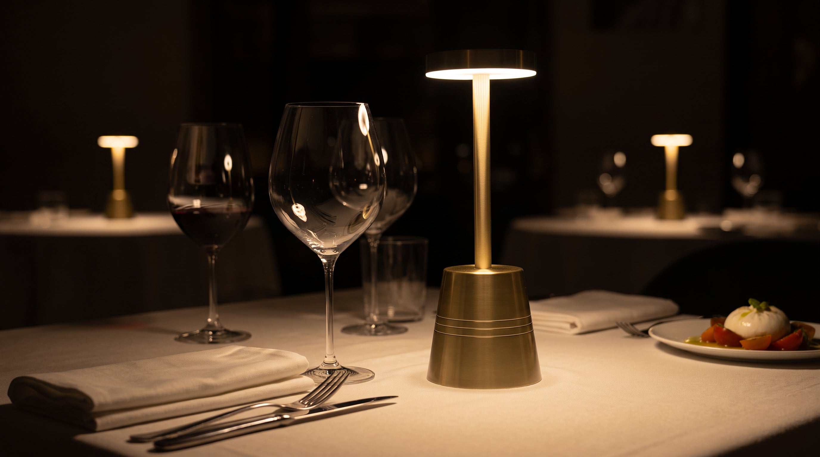Sienna lamps lit on set tables in a panelled dining room