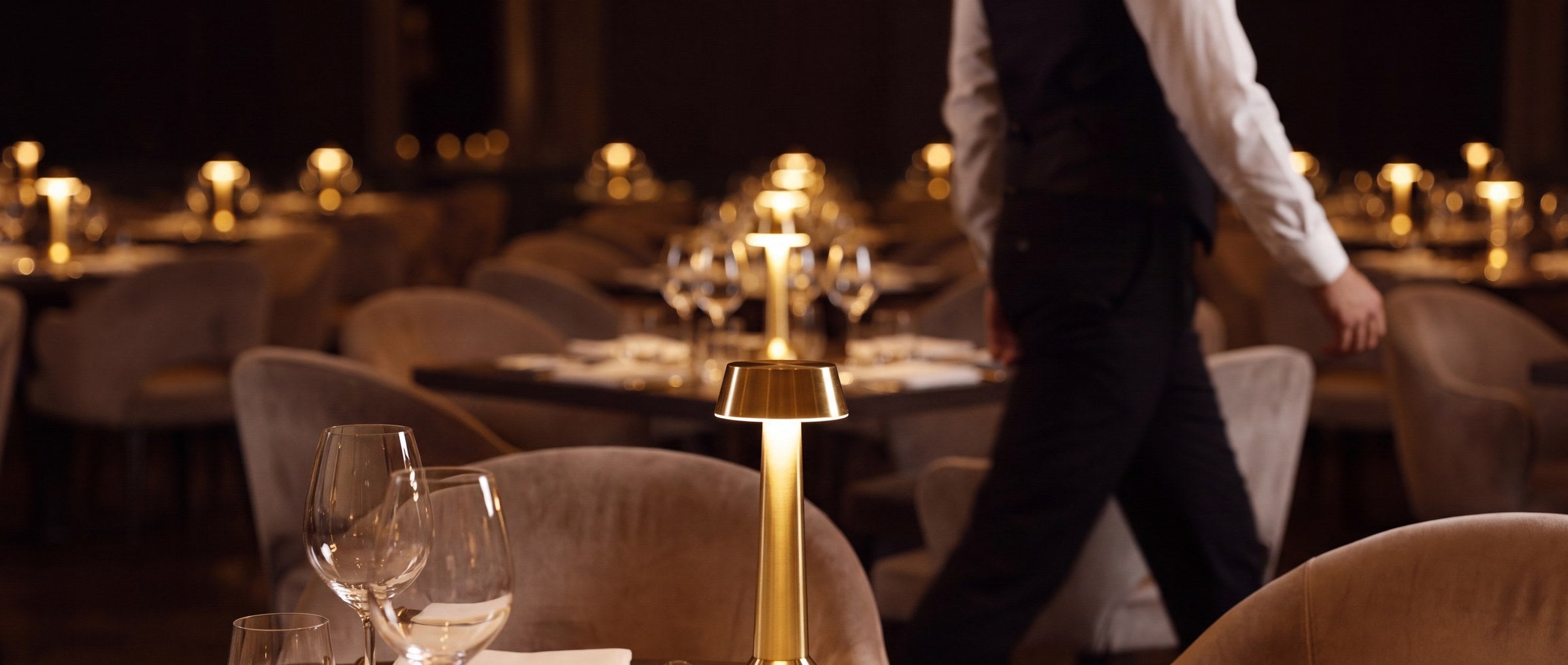 A dining room in service: one table in front, more lit tables receding into the room.