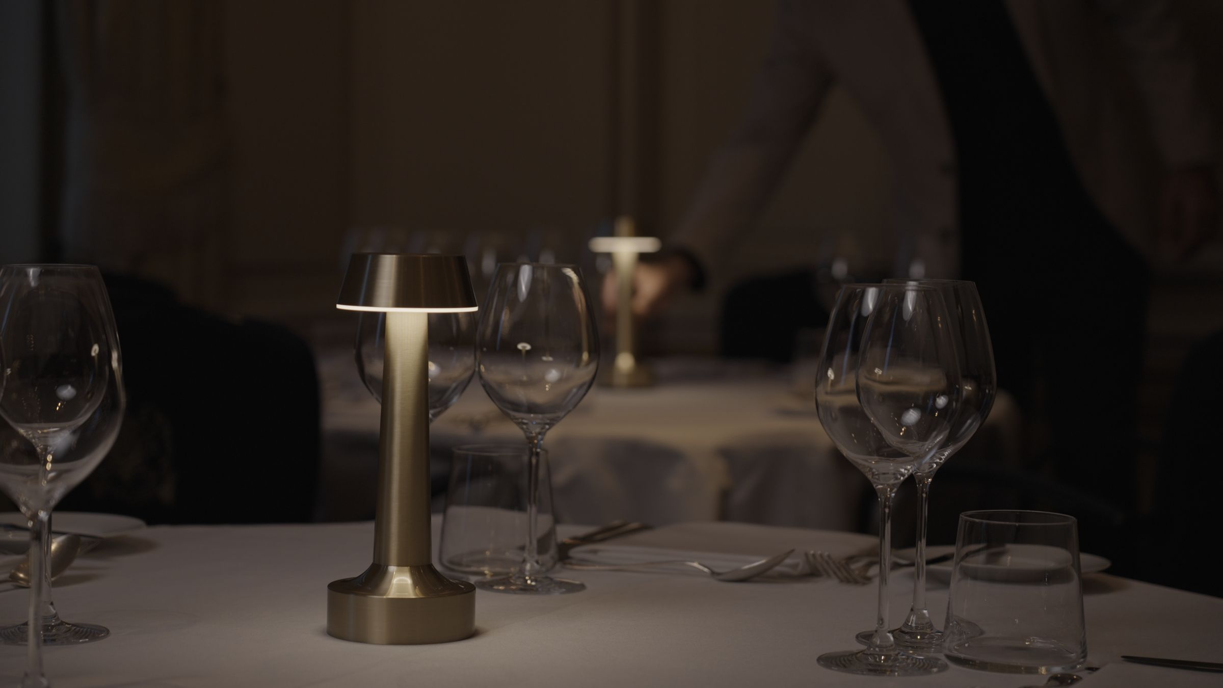 A cordless brass lamp on a table in a warm restaurant booth