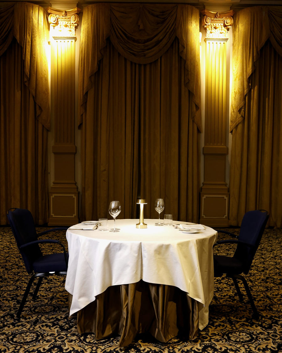 A dressed table lit by a Clarté lamp in a gilded hotel ballroom