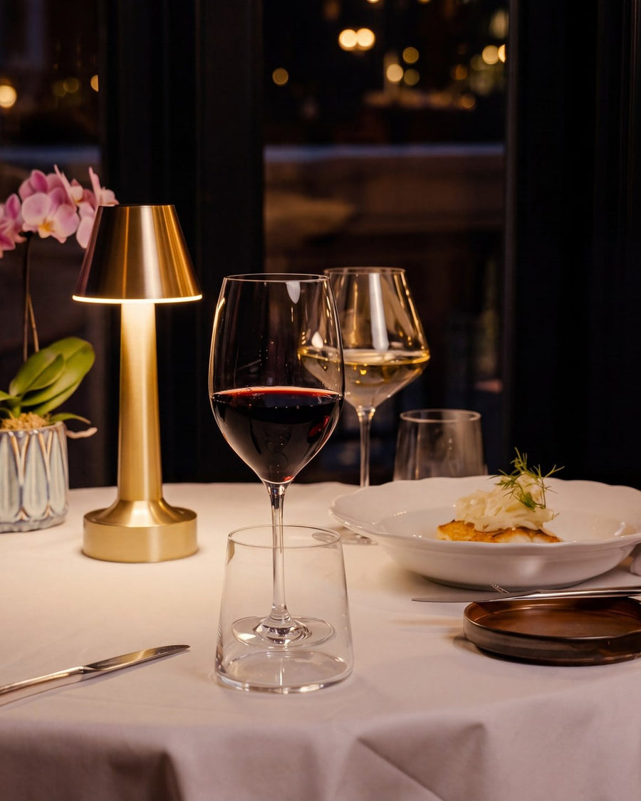 A Clarté lamp on a window table set for dinner