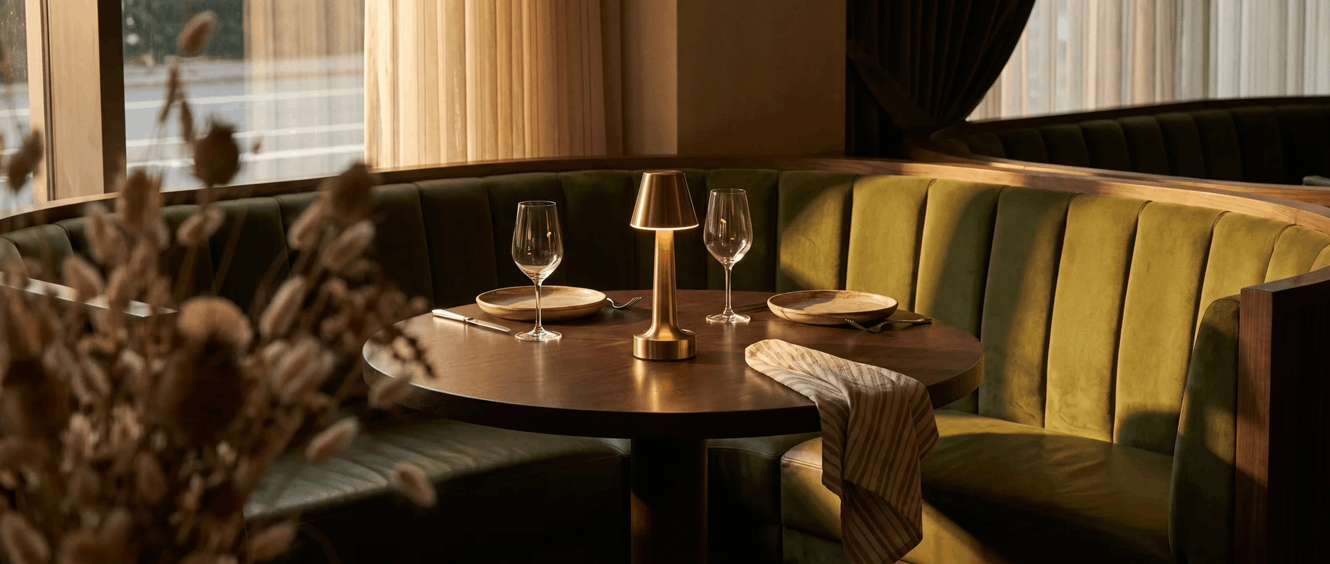 A cordless brass lamp on a table in a warm restaurant booth
